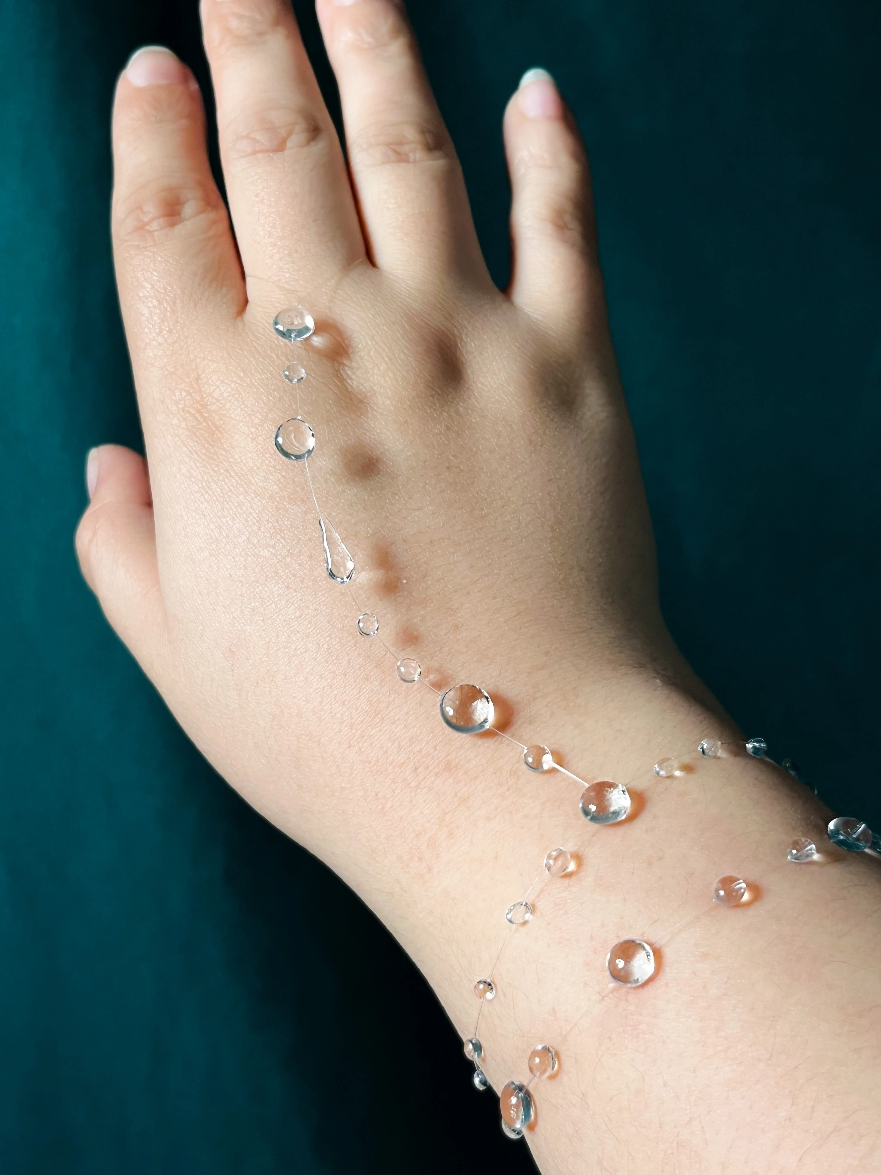 Clear resin dewdrops resting along the hand